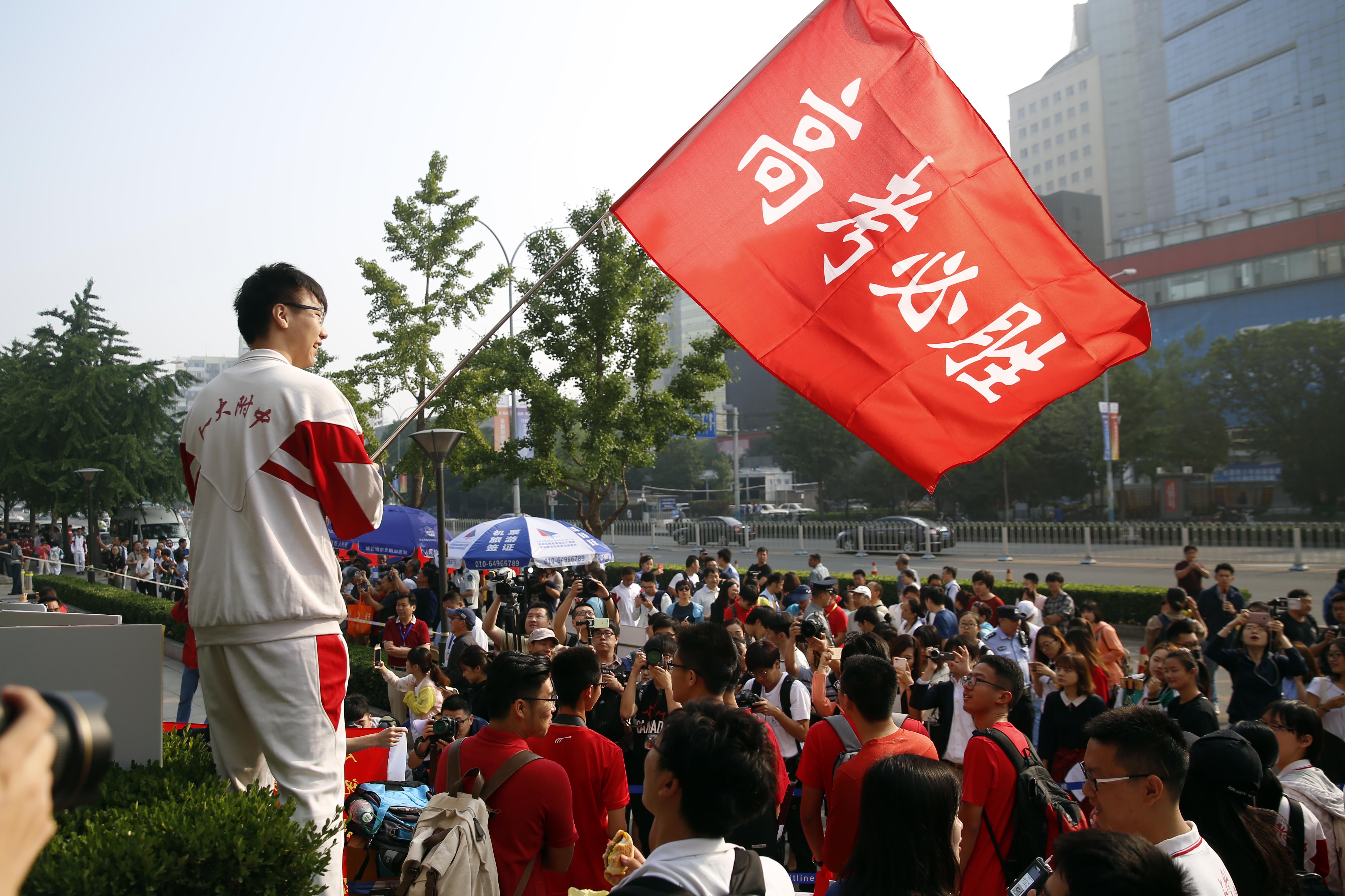 北京某考点外，学生挥舞「高考必胜」红旗为考生加油（中新社）