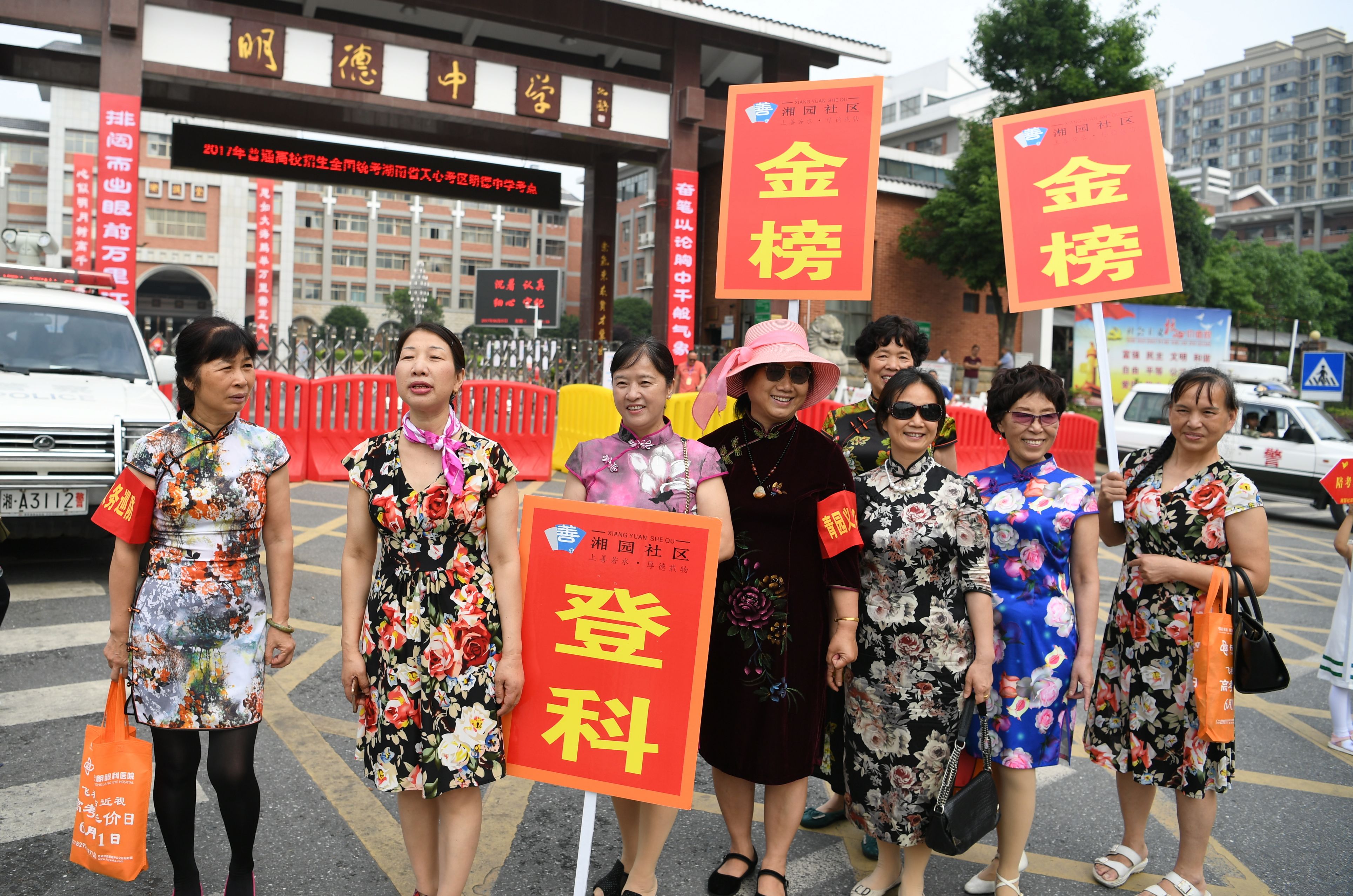 有身着旗袍的家长高举「金榜登科」的牌匾为考生加油，希望考生「旗开得胜」（中新社）