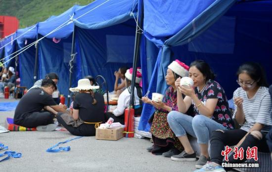 8月10日，四川九寨沟「8.8」地震震源中心附近的临时安置点，受灾村民在帐篷边吃饭。中新社