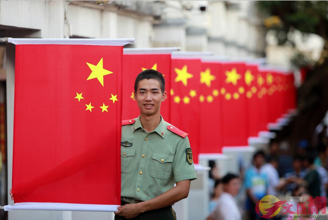 驻守在中英街上的「沙头角模范中队」官兵在国庆节来临之际与深港居民悬挂国旗营造节日氛围(记者郭若溪摄)