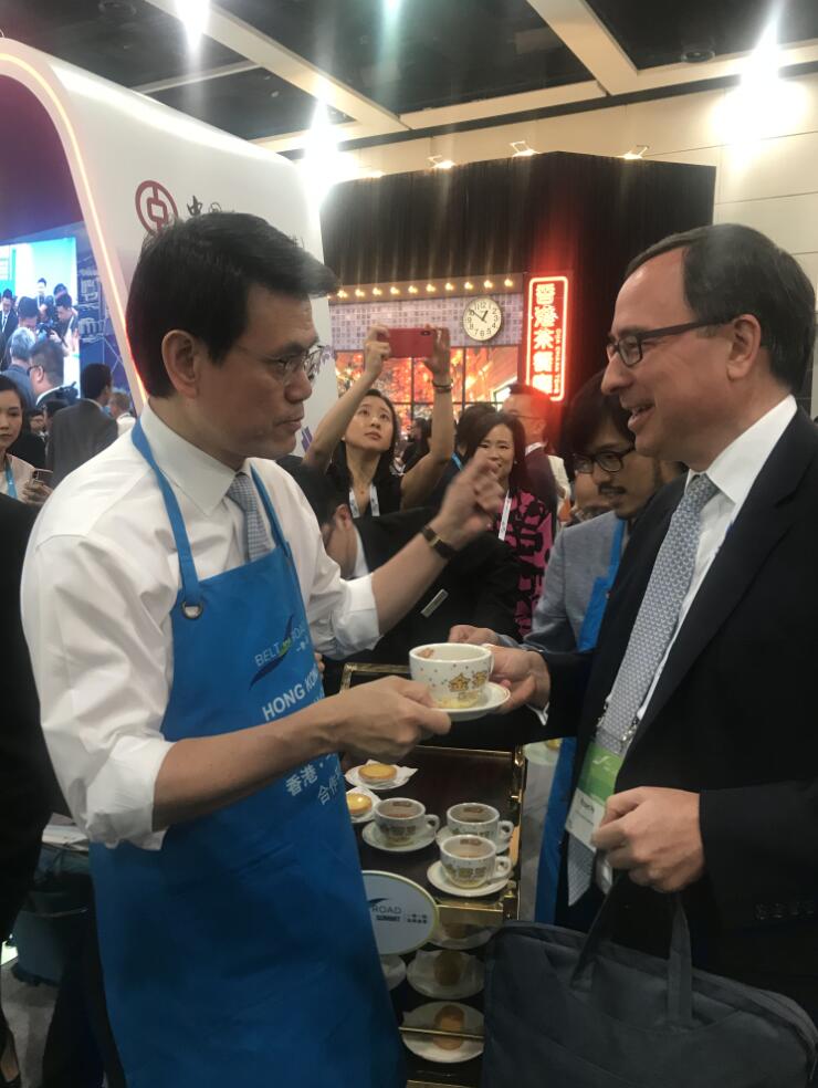 香港商務及經濟發展局局長邱騰華在「一帶一路高峰論壇」茶歇期間，賣力「推銷」港式奶茶(網友提供) 