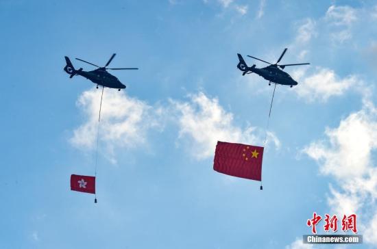 7月1日，香港特別行政區政府在金紫荊廣場舉行隆重的升旗儀式，慶祝香港回歸21周年。圖為兩架直升機懸掛五星紅旗和香港區旗經過金紫荊廣場上空。中新社