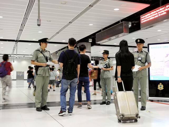 海關人員於暑假期間在邊境管制站派發傳單，提醒旅客切勿攜帶禁運或受管制物品進出香港