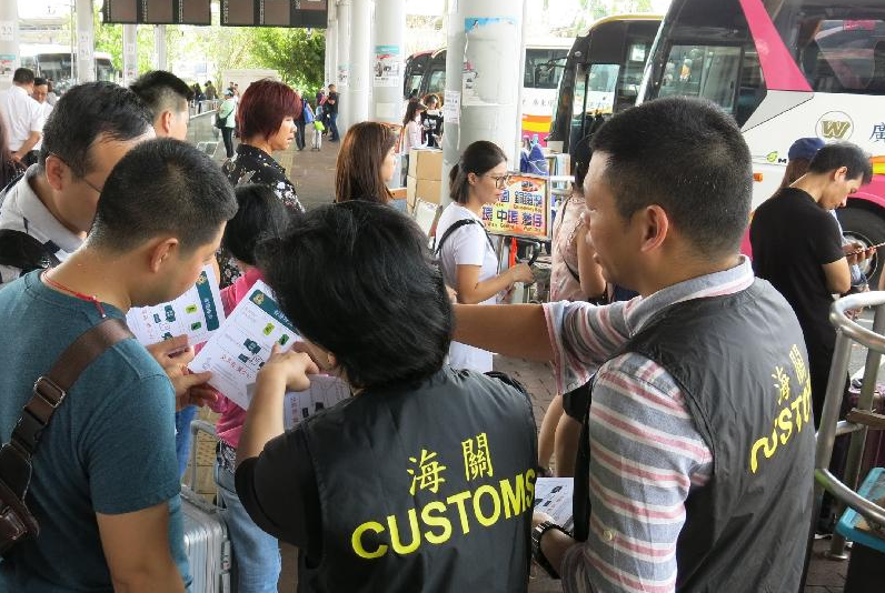 香港海關展開u極光v行動A加強巡查A以保障消費者C圖示海關人員在過境巴士站派發提醒訪港旅客精明消費的單張C