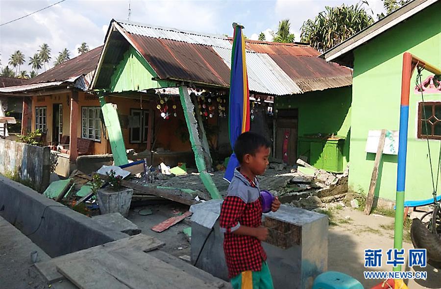 印度尼西亞抗災署9月28日公布的這張照片顯示A在中蘇拉威西省棟加拉縣A一名男孩經過地震中受損的房屋C]印度尼西亞抗災署供圖 新華社發^