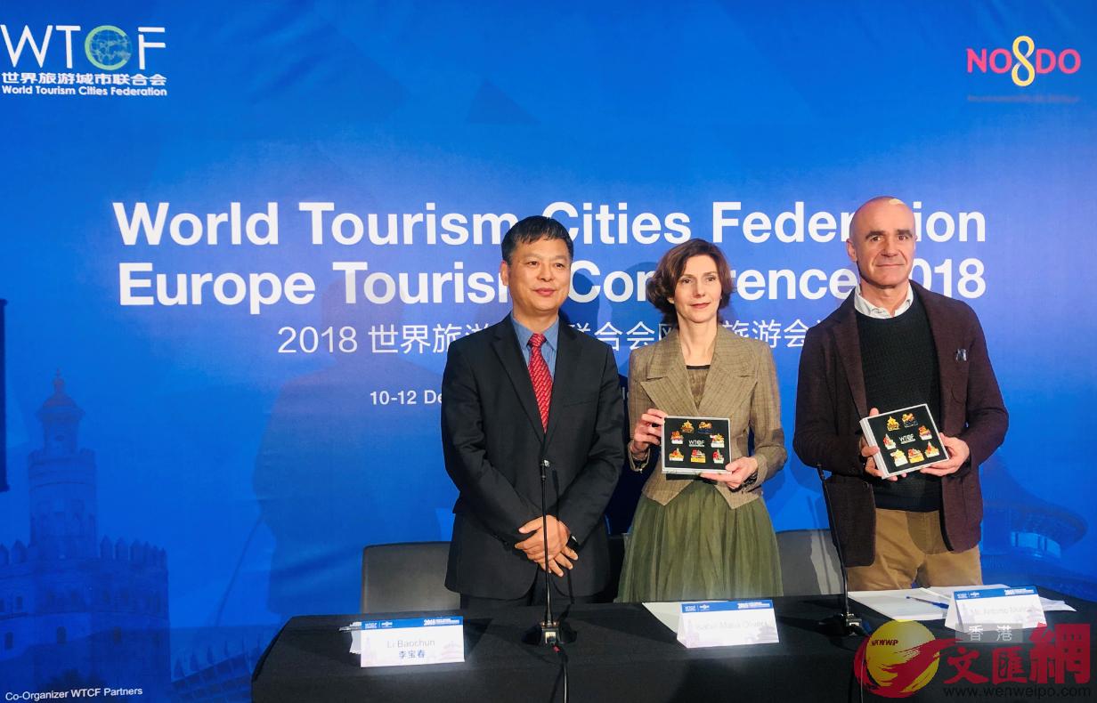 世界旅遊城市聯合會常務副秘書長李寶春(左)與西班牙及塞維利亞市負責人互贈紀念品。記者秦占國 攝 