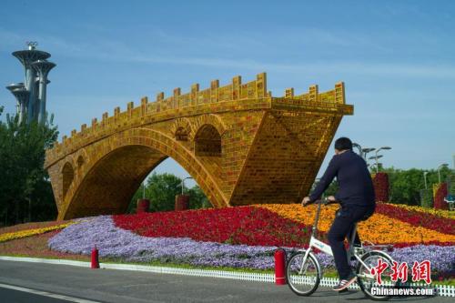 資料圖G北京市民騎車經過北京國家會議中心前廣場的u絲路金橋v立體花壇C中新社