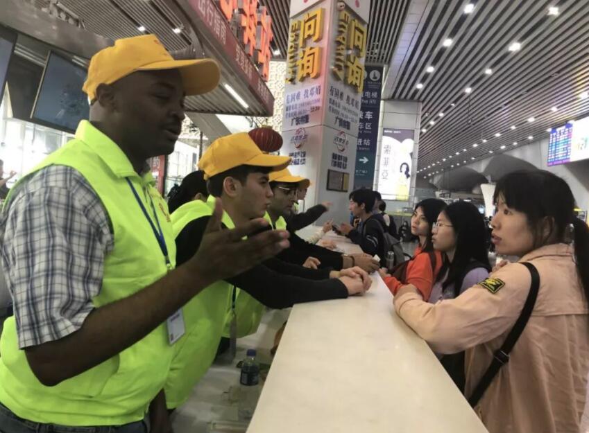 在廣州讀大學的外國小伙艾文用中文與前來查詢的旅客交流C(受訪者供圖)