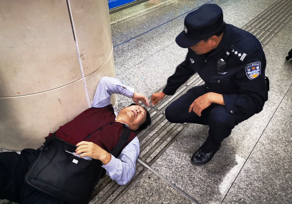 皇崗邊檢民警向突發疾病癱在地上的香港老人了解情況]皇崗邊檢站提供^