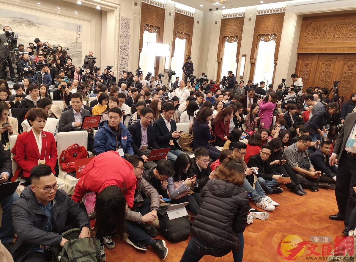 今年會場特別允許記者們在第一排座位前席地而坐A給不少沒搶到位置的記者二次爭取機會]大文全媒體記者 郭若溪 攝^