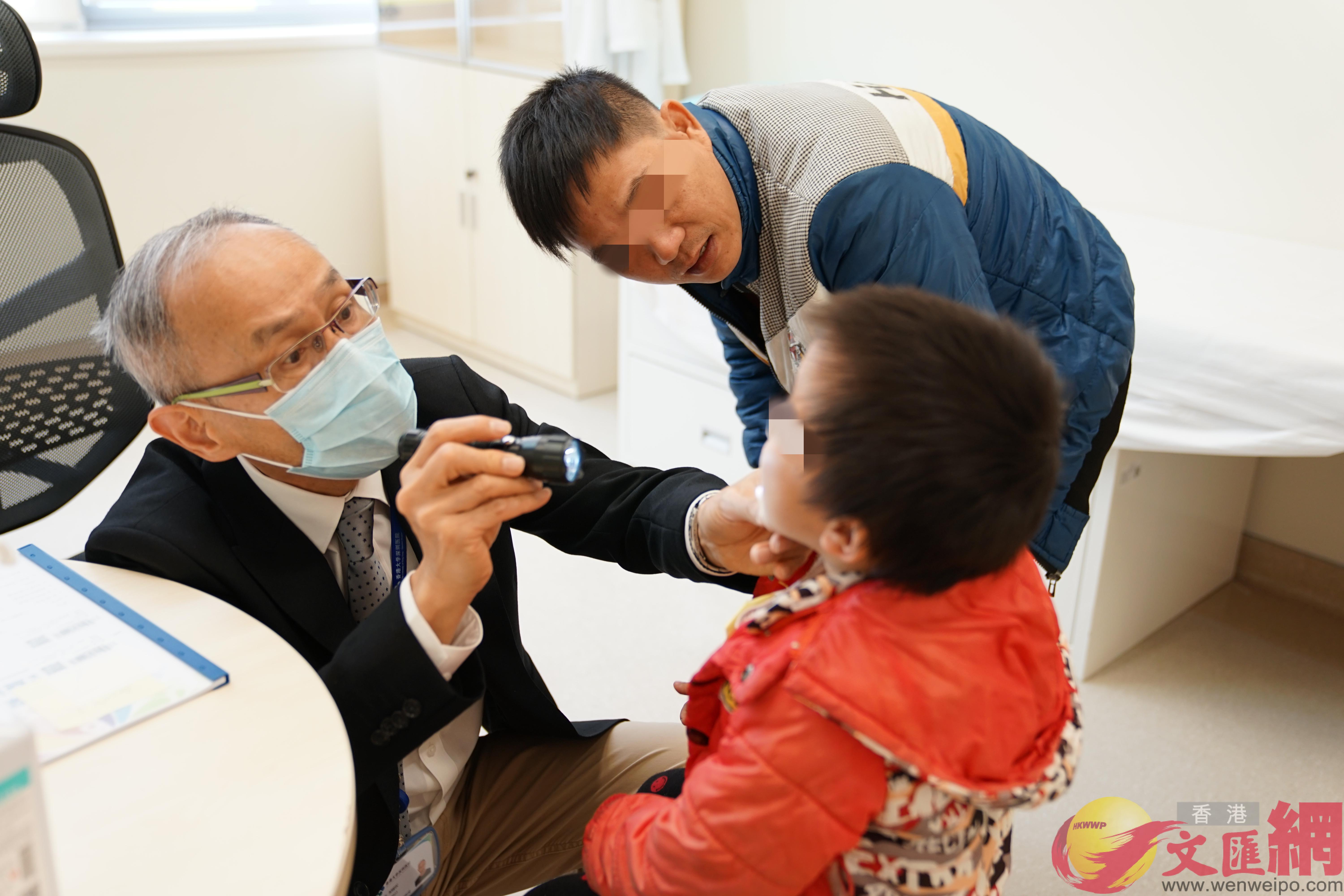 第八屆唇顎裂公益行動中香港大學深圳醫院鄒錫權醫生為患兒做檢查 C]記者 郭若溪 攝^