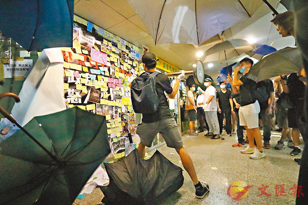 有黑衣人在其他人打傘遮掩下A就地取材執起商場金屬流動欄柵擊向辦事處玻璃C香港文匯報記者 攝