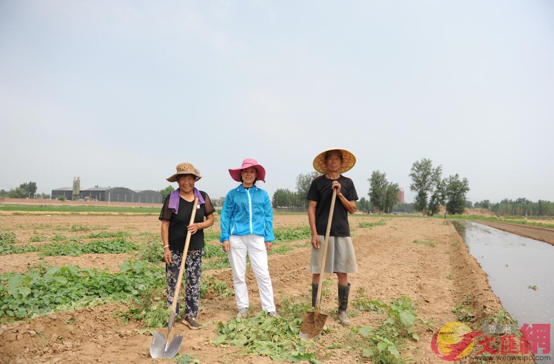 蔣曉霞(中)在實驗田與工人合影(記者顧大鵬攝)