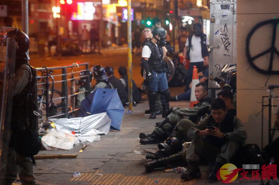 接近午夜A脫力的警員在路邊坐地休息C香港文匯報記者攝 