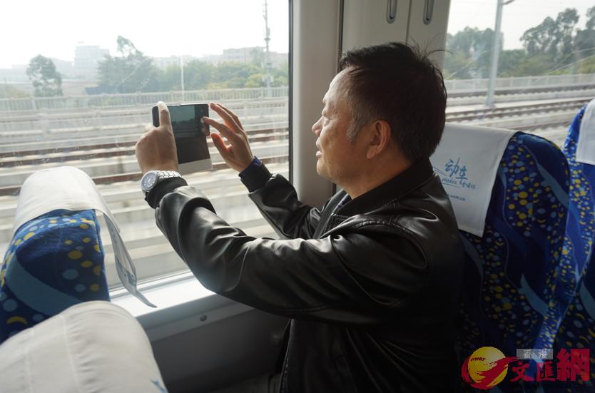 港人劉先生在用手機拍攝沿途的風景 記者 郭若溪攝