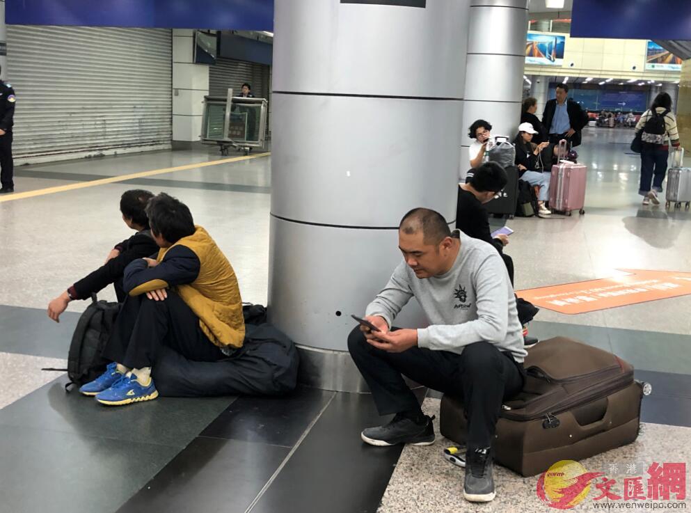 在廣州火車東站候車的湖南籍外來工劉剛為]圖右一^通過手機與家人視頻聊天C]方俊明攝^