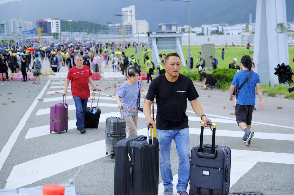 9月1日，由於暴徒堵塞交通，旅客只能拖著行李跨越路障走進香港國際機場。(新華社資料圖片)
