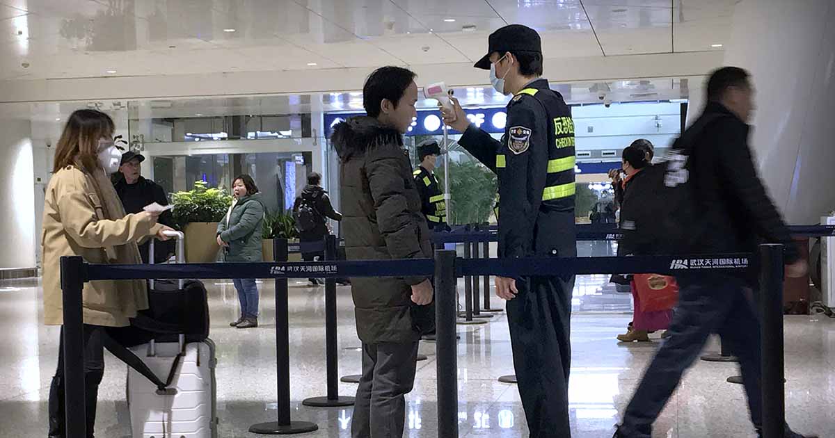 武漢天河國際機場工作人員對旅客使用紅外線溫度計檢測體溫。（美聯社）
