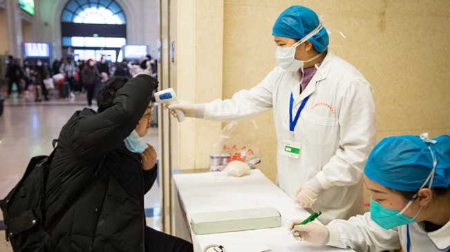 1月22日，武漢市漢口火車站醫護人員對進站旅客進行體溫檢測（新華社）