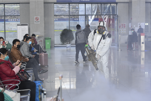 十餘位志願者手持重型消毒機器，對長沙火車站內外進行消毒殺菌。（中新社）