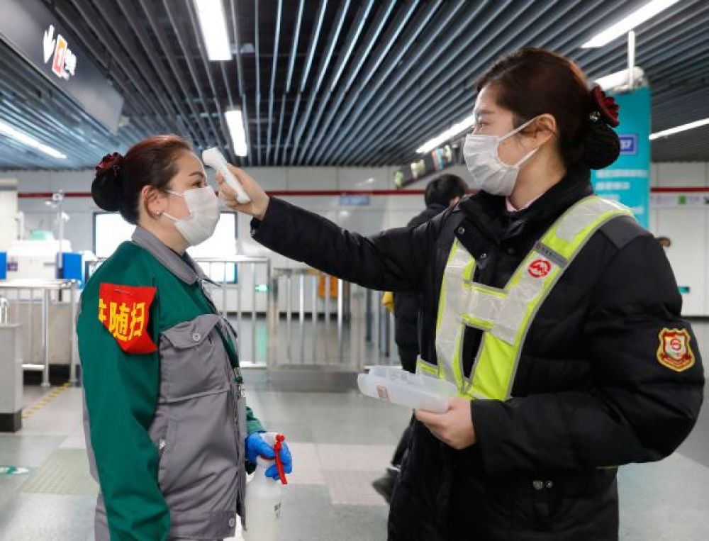 2月10日 上海地鐵工作人員為負責保潔消毒的員工測量體溫C當日A上海許多企業開始復工C上海地鐵實施嚴格疫情防控措施A確保旅客安全(新華社)