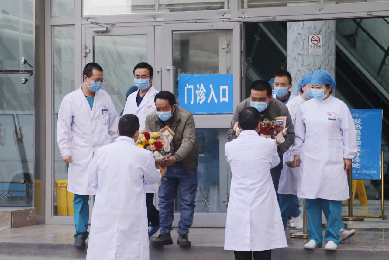 青海省第四人民醫院醫護人員為最後兩名確診新冠肺炎治癒出院患者送上鮮花(中新社)