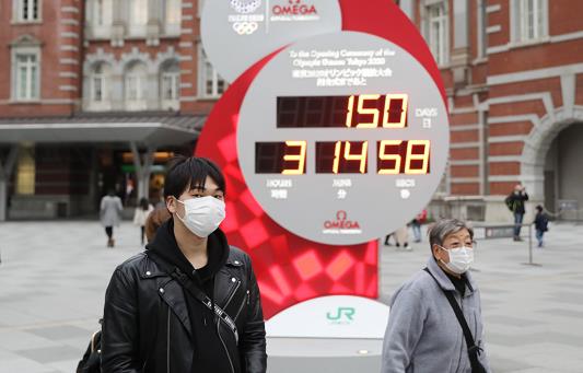 2月25日，戴口罩的行人經過顯示東京奧運會倒計時的電子屏（新華社圖片）