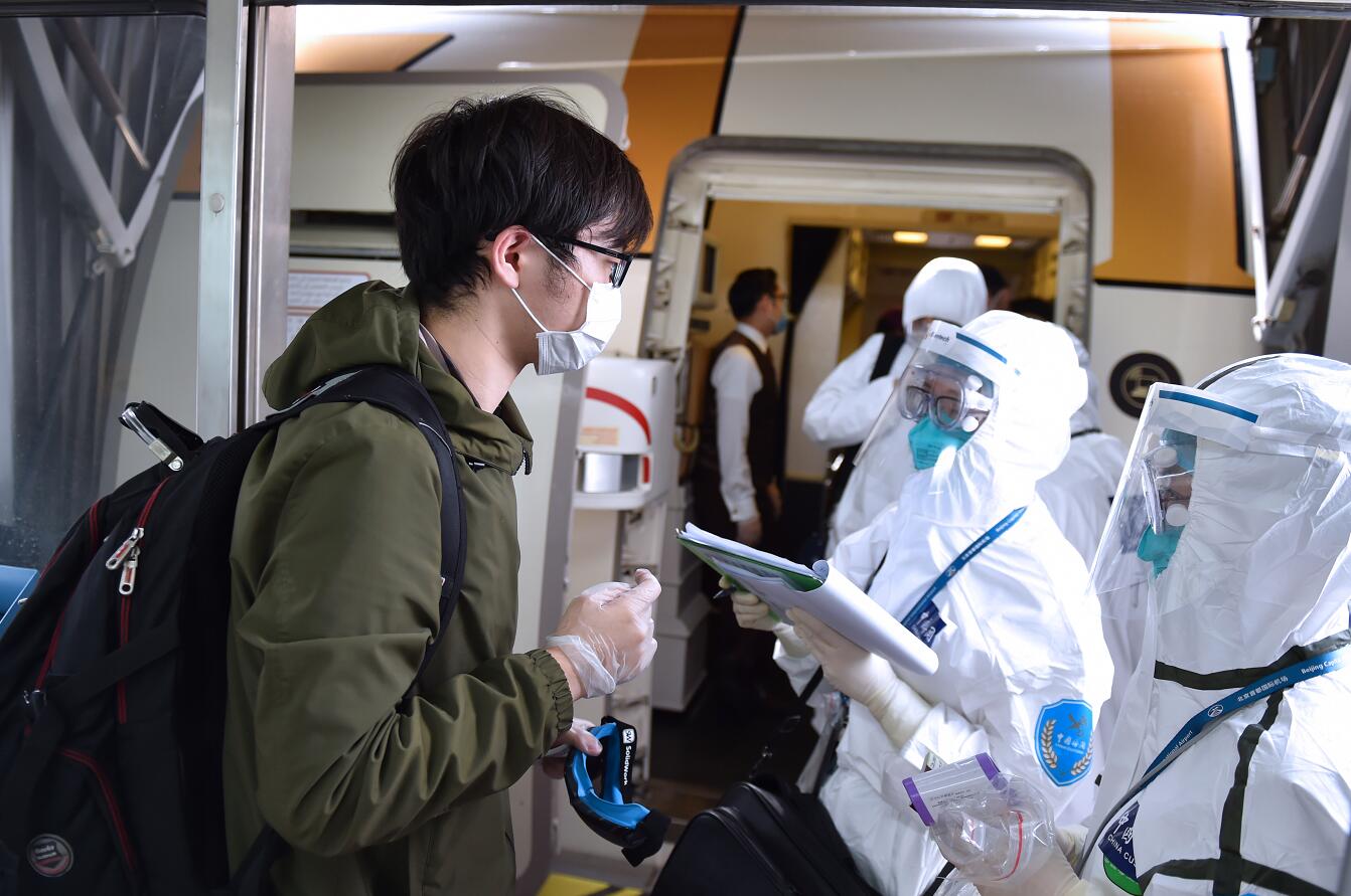 內地海關工作人員在飛機艙門處對入境人員相關情況進行記錄]新華社圖片^