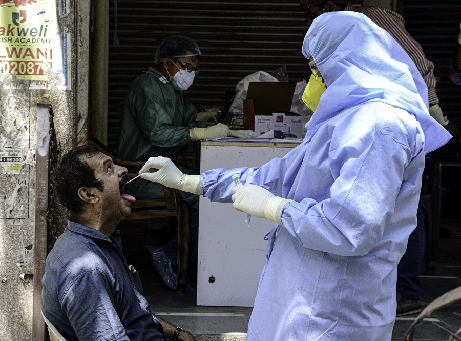 4月13日印度孟買一醫護人員為一名男子進行新冠病毒檢測取樣（新華社）