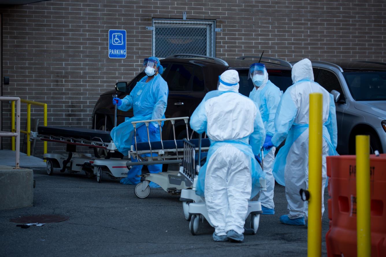 美國紐約一家醫院外，醫護人員將死亡患者遺體送往臨時冷藏車後推著空床返回。新華社 