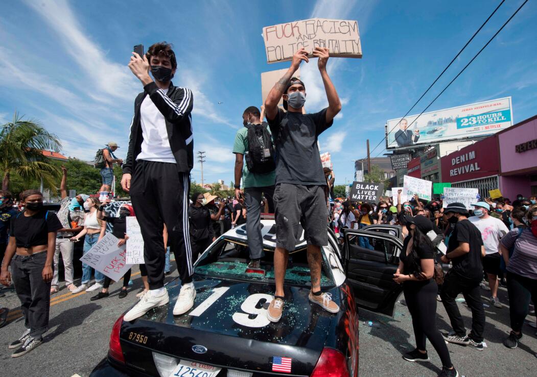 示威者站在2020年5月30日在加利福尼亚州洛杉矶费尔法克斯区的一辆砸碎的警车上A抗议乔治P弗洛伊德]George Floyd^的死亡C資料圖G法新社