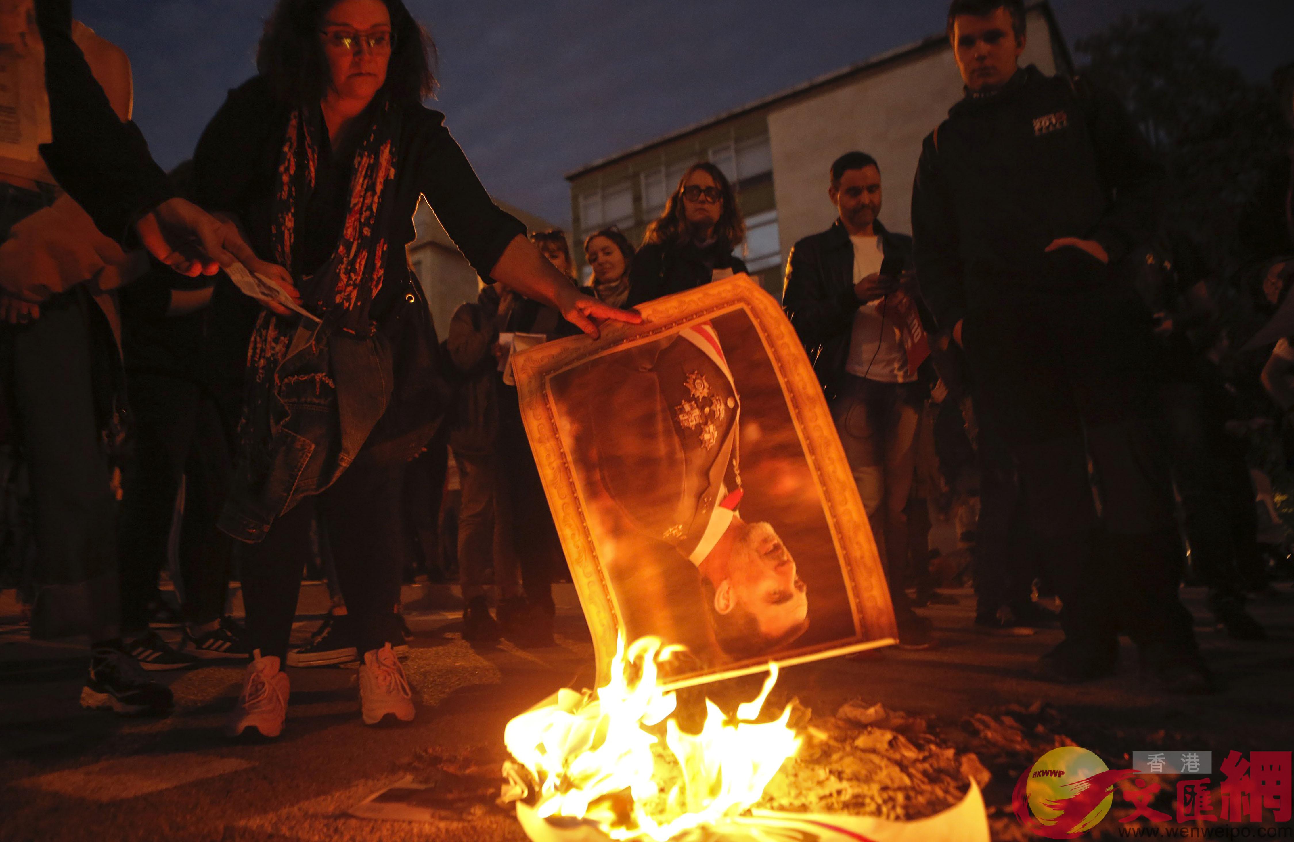 抗議者在會議中心外舉行的抗議活動中焚燒西班牙國王費利佩的肖像]美聯社^