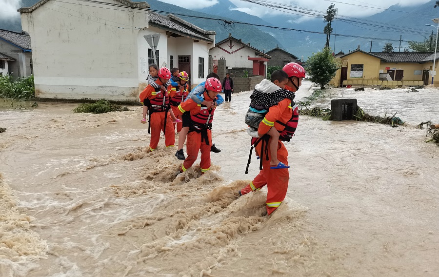 6月27日A四川省涼山彝族自治州出現強降雨天氣A圖為消防救援人員在洪水中背着孩子們轉移C]中新社^