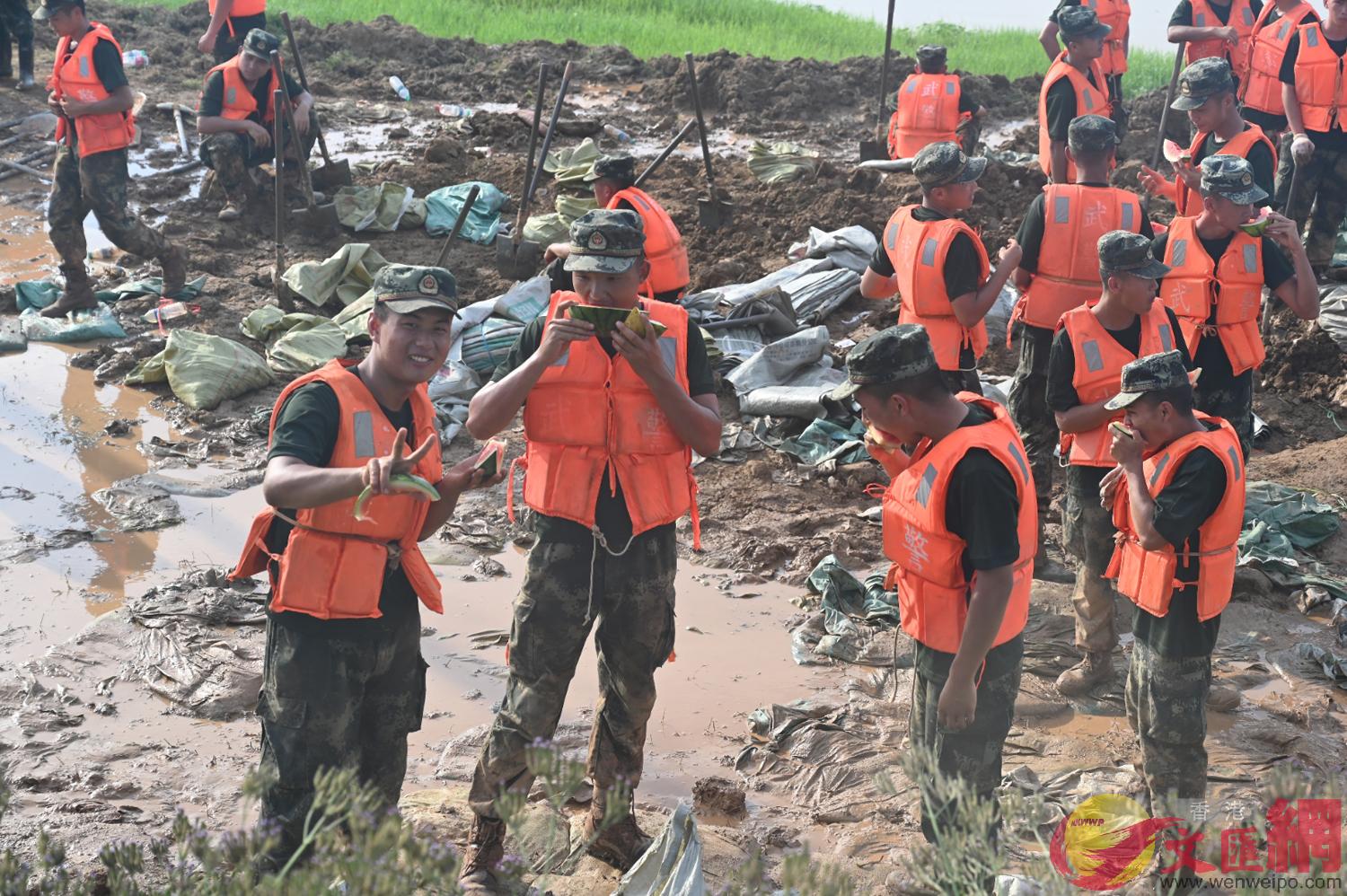 抗洪搶險的武警官兵在吃村民們送來的西瓜]王逍攝^