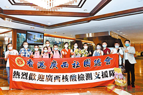 內地核酸檢測支援隊共89名成員抵達香港，香港廣西社團總會、香港福建社團聯會的代表手持歡迎橫幅迎接。 中新社